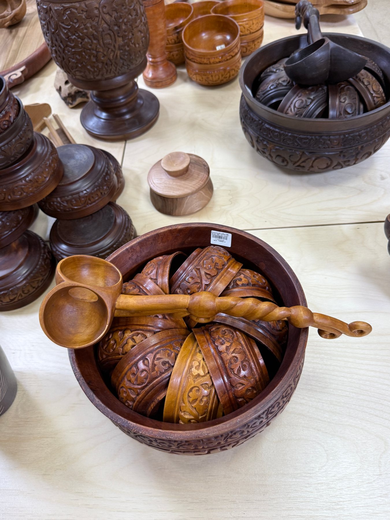 A close display of carved wooden bowls, cups and long-handled ladles.