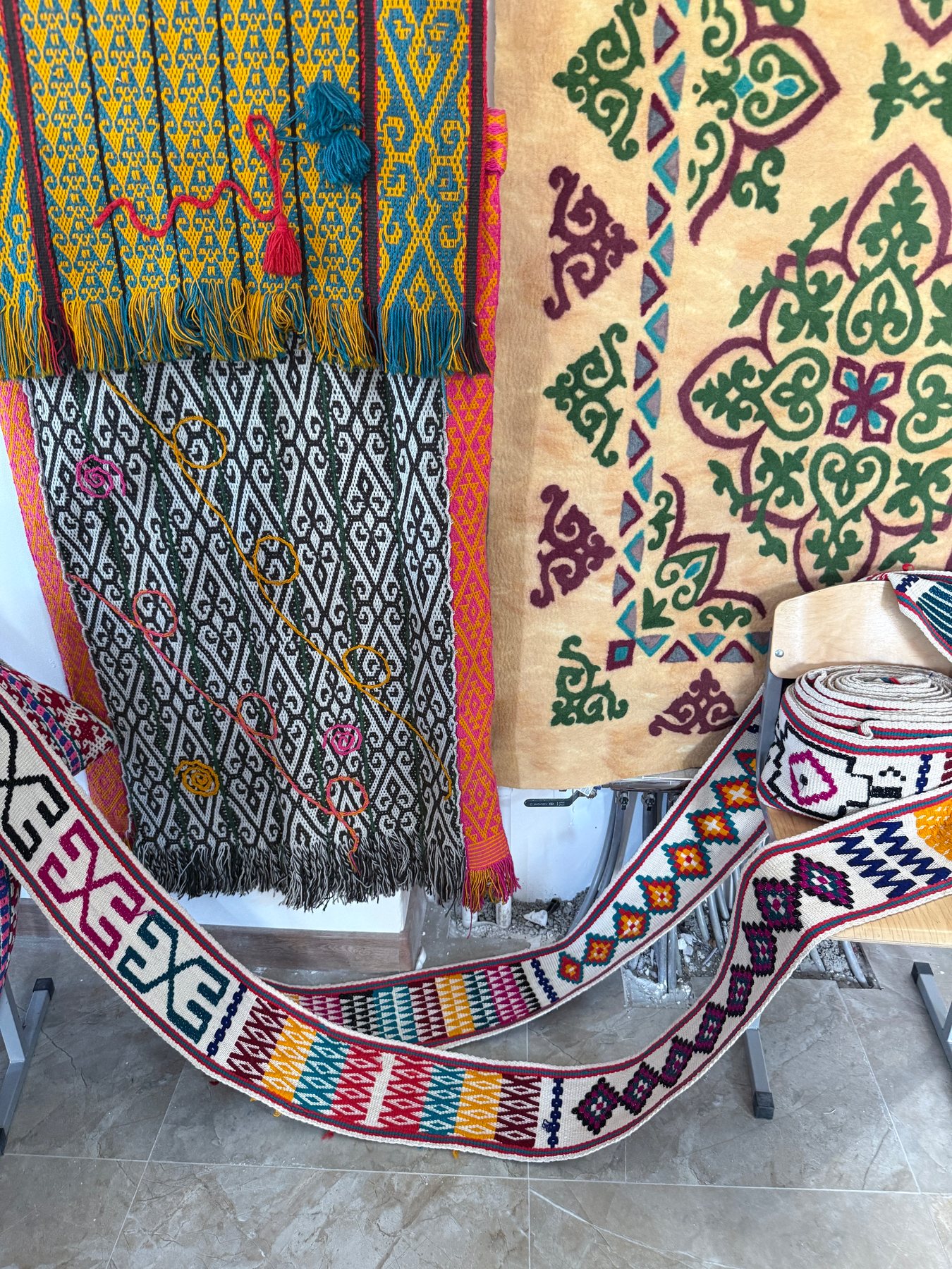 A close display of richly coloured woven bands, patterned textiles and felt pieces.