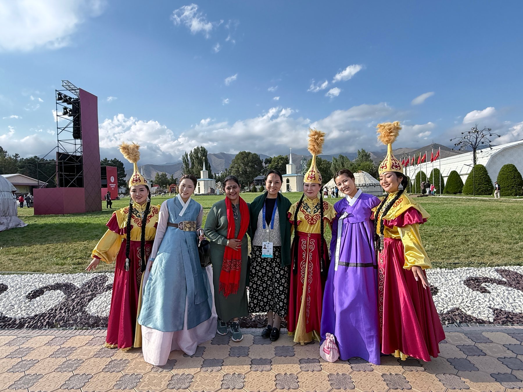 A group of international visitors in varied dress standing together on festival grounds.