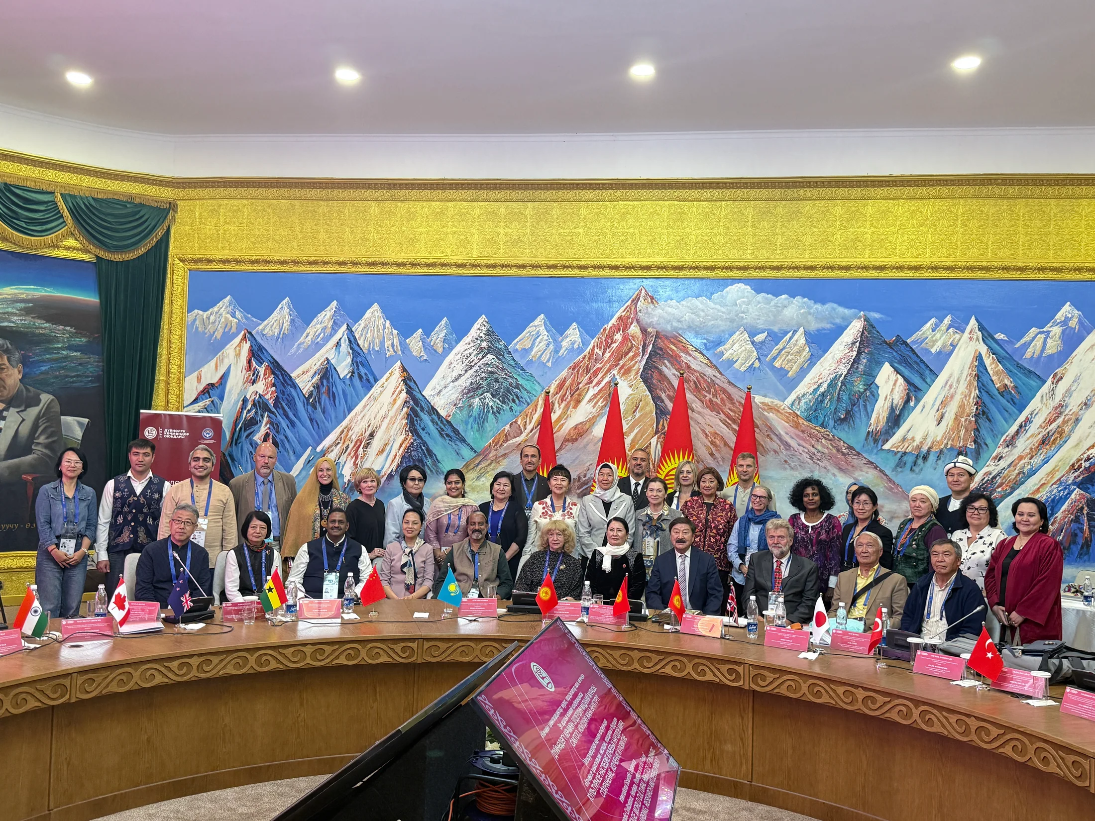 International delegates pose behind a conference table with national flags and Kyrgyz flags